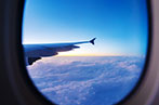 Looking out of an airplane window at a cloudy sunrise.