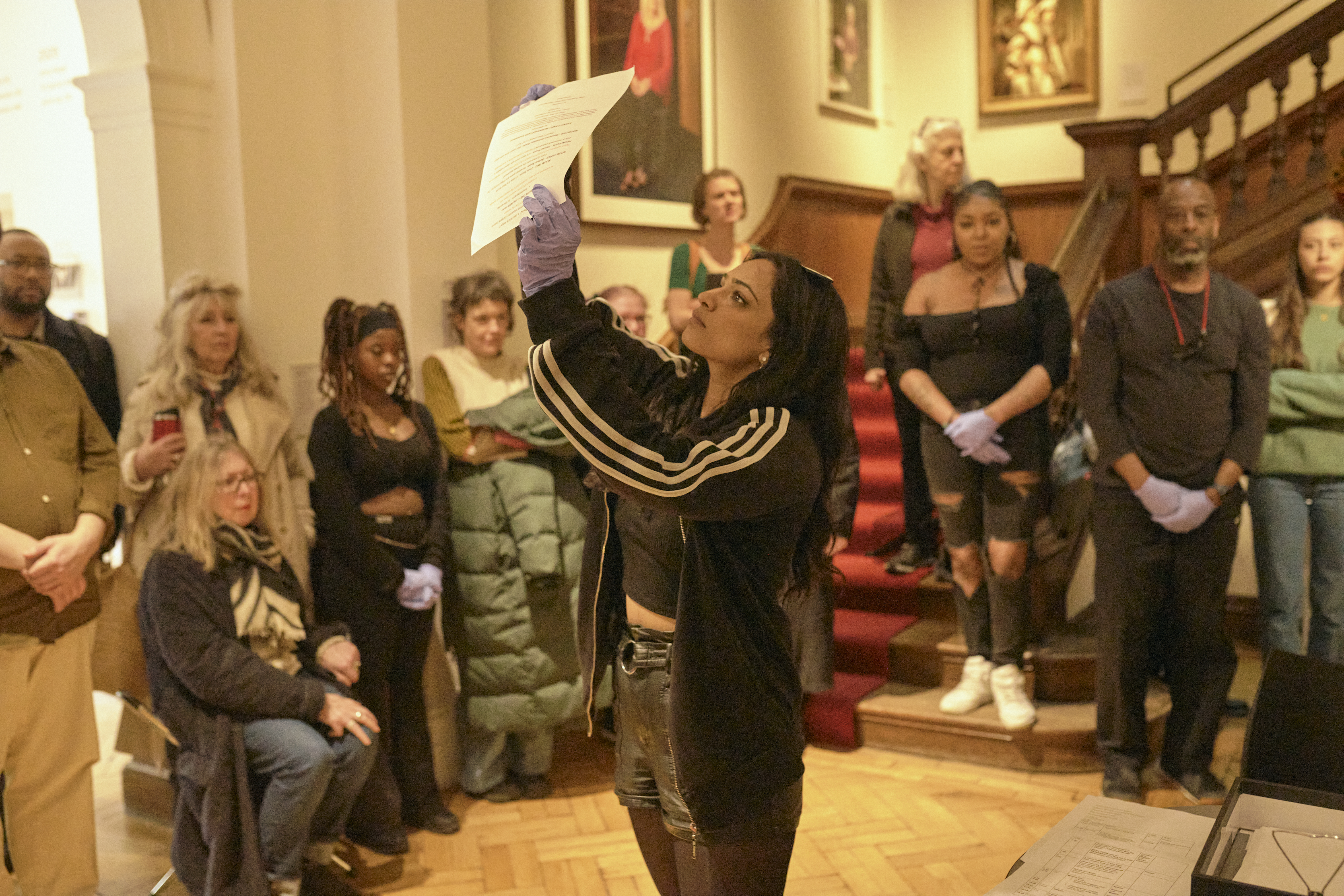 A person wearing gloves holds up a piece of paper as part of a theatre production