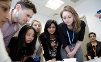 Group of students and teachers looking down at machine