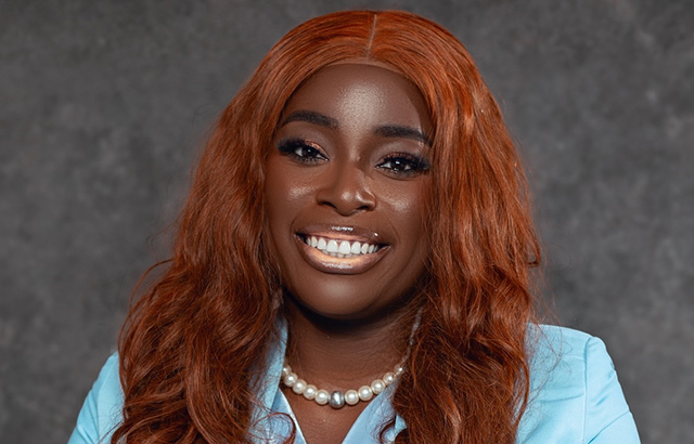 Iyanujesu Oguntunji smiling. She is wearing pearls and a baby blue jacket and top.