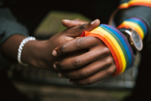 Hands clasped with a pride ribbon and braclet
