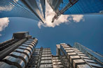 A photo looking directly up at glass office buildings from the street.
