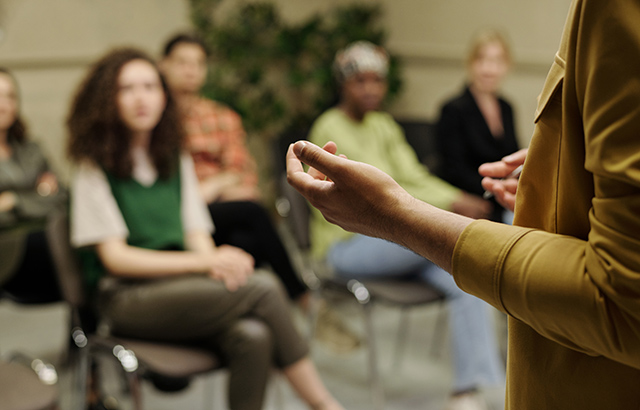The hands of someone speaking to a group of young people.