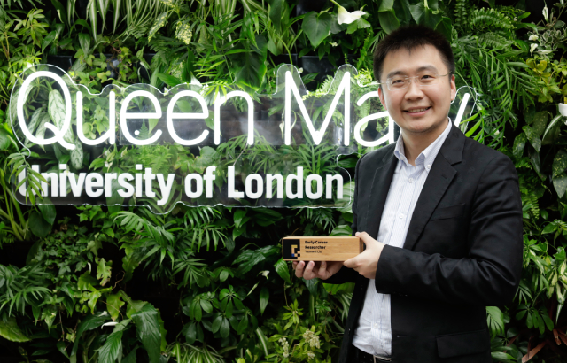 Dr Yuanwei Liu with his Early Career Researcher prize, standing in front of a green wall