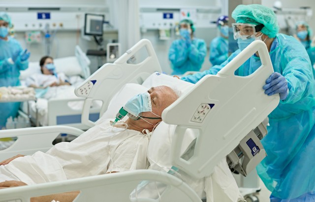 Patient on ventilator lying in hospital bed as medical professional moves his bed. Credit: xavierarnau/iStock.com