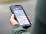 A woman holding her smartphone checking a contact tracing app. Credit:mphillips007/iStock.com