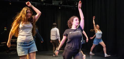 On a stage, a group of people dance experimentally