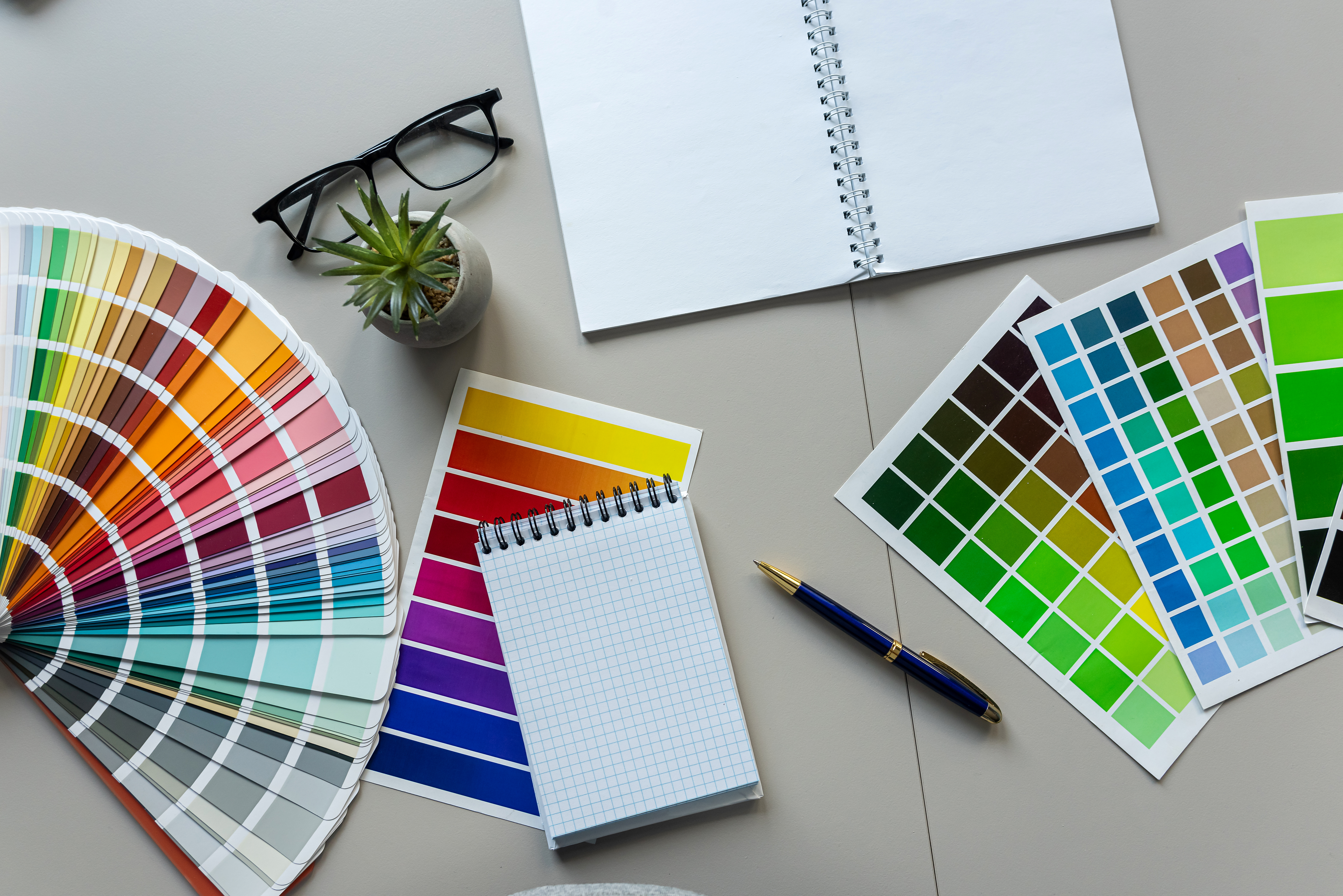 A notebook, art materials and colour charts fanned out