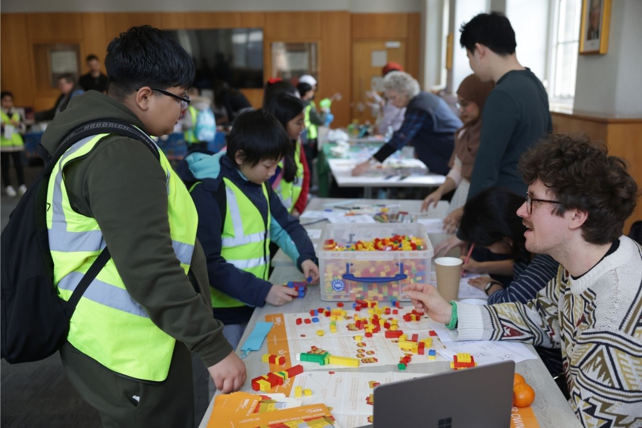 Researchers leading a lego physics activity with children at a science fair