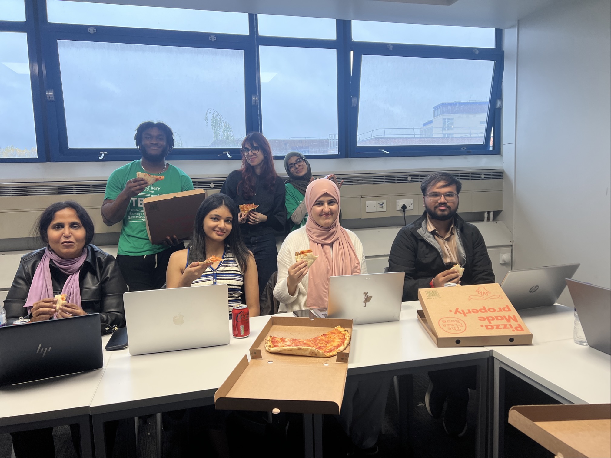Student sitting at the session, eating pizza.